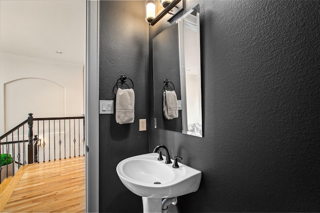 bathroom with crown molding, sink, and hardwood / wood-style floors