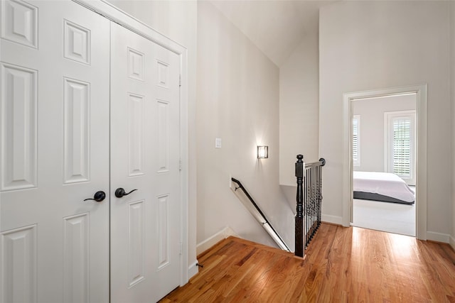 stairs with hardwood / wood-style floors and vaulted ceiling