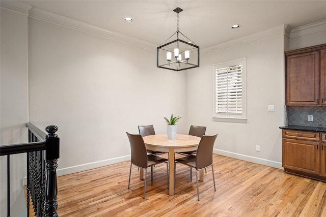 dining room with crown molding, light hardwood / wood-style floors, and a notable chandelier