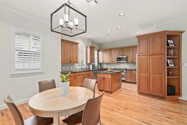 kitchen featuring pendant lighting, ornamental molding, stainless steel appliances, and a kitchen island