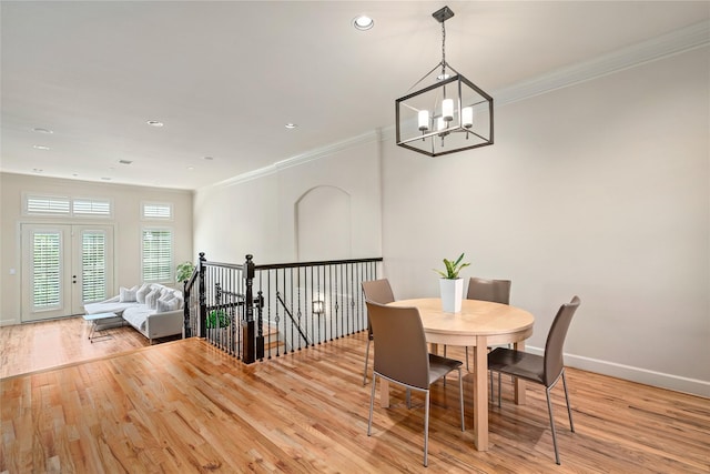 dining area with crown molding, an inviting chandelier, and light hardwood / wood-style floors