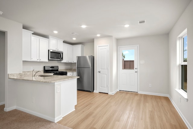 kitchen featuring sink, appliances with stainless steel finishes, white cabinetry, light stone counters, and kitchen peninsula