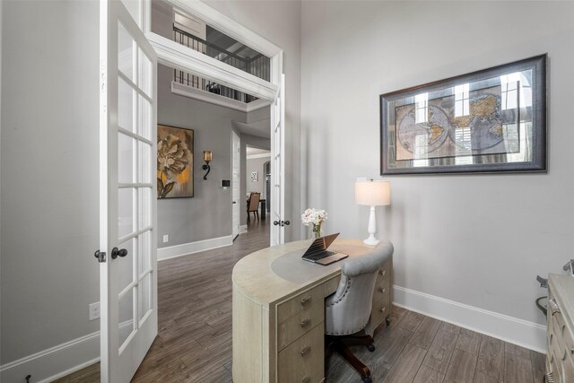 home office with french doors, a towering ceiling, and dark hardwood / wood-style floors