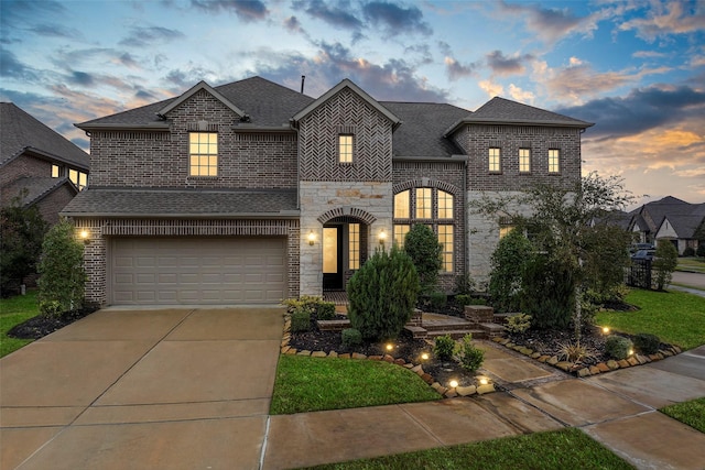 french country home with driveway, stone siding, a shingled roof, and brick siding