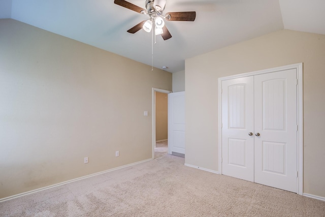 unfurnished bedroom featuring vaulted ceiling, light colored carpet, ceiling fan, and a closet