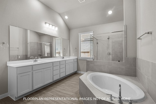 bathroom featuring lofted ceiling, a sink, wood finished floors, double vanity, and a stall shower