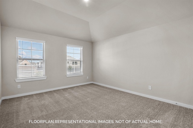 empty room featuring vaulted ceiling, carpet, and baseboards