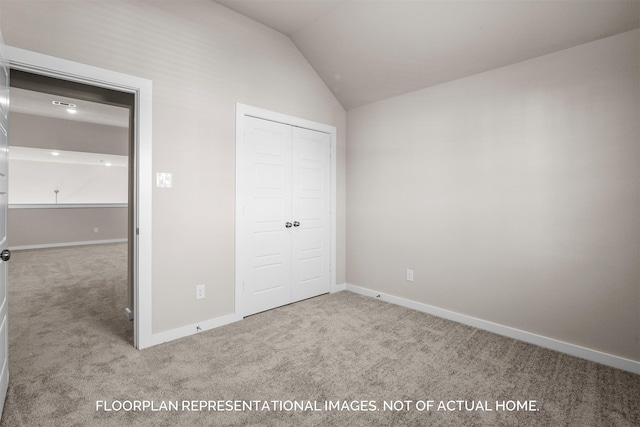 unfurnished bedroom with vaulted ceiling, carpet floors, a closet, and baseboards