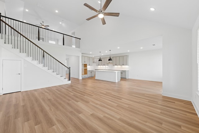 8411 Oceanmist Cove Dr, Cypress, TX 77433 - unfurnished living room with ceiling fan, recessed lighting, stairs, high vaulted ceiling, and light wood-style floors