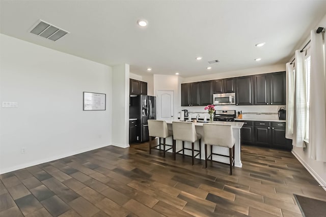 kitchen with dark wood-style floors, a breakfast bar, light countertops, visible vents, and appliances with stainless steel finishes