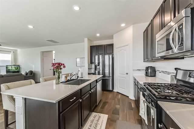 kitchen featuring stainless steel appliances, dark wood-style flooring, a sink, and light countertops