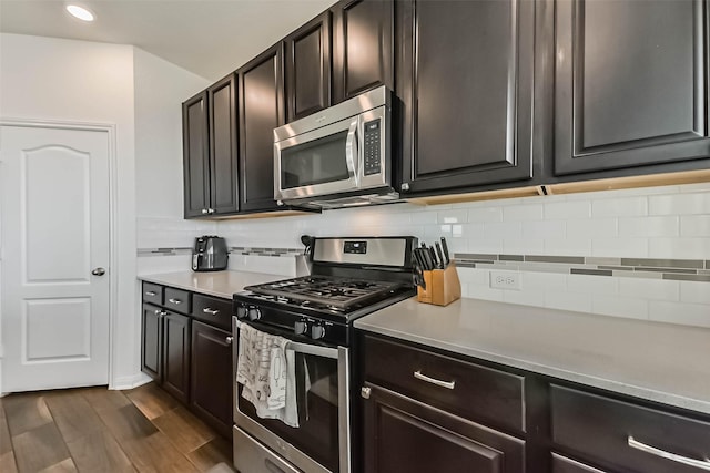 kitchen featuring dark wood-type flooring, stainless steel appliances, backsplash, and light countertops