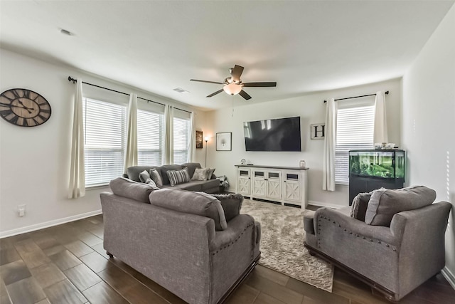 living room with baseboards, visible vents, a ceiling fan, and dark wood-type flooring