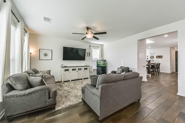 living room featuring wood tiled floor, visible vents, ceiling fan, and baseboards