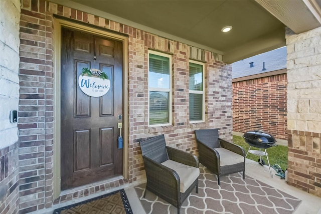 view of exterior entry featuring a garage, brick siding, and a porch