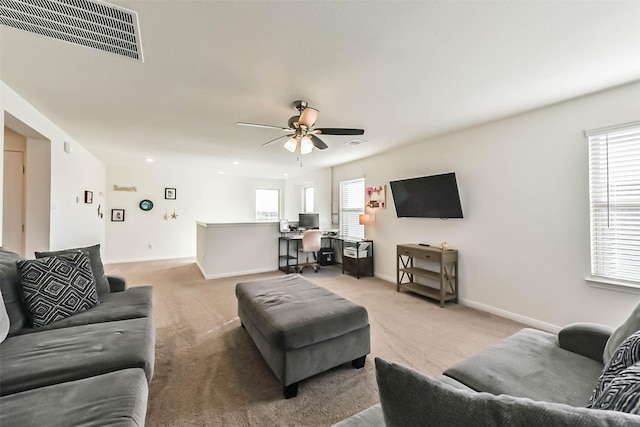 living area with light carpet, baseboards, visible vents, and ceiling fan