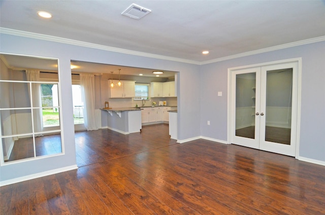 unfurnished living room with baseboards, visible vents, dark wood finished floors, ornamental molding, and french doors