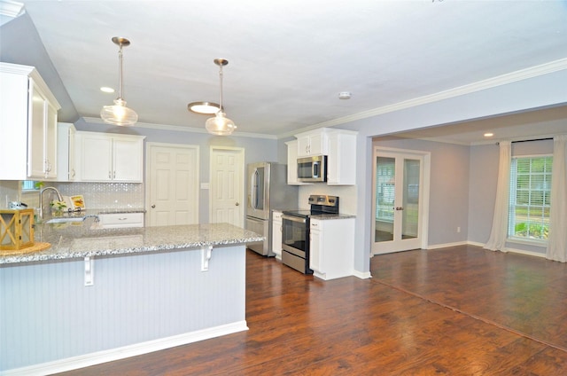 kitchen featuring appliances with stainless steel finishes, a sink, decorative light fixtures, and white cabinets