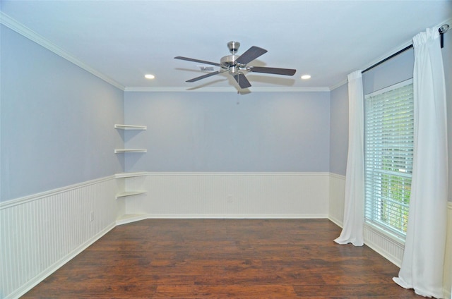 empty room featuring a wainscoted wall, a ceiling fan, dark wood-style floors, and crown molding