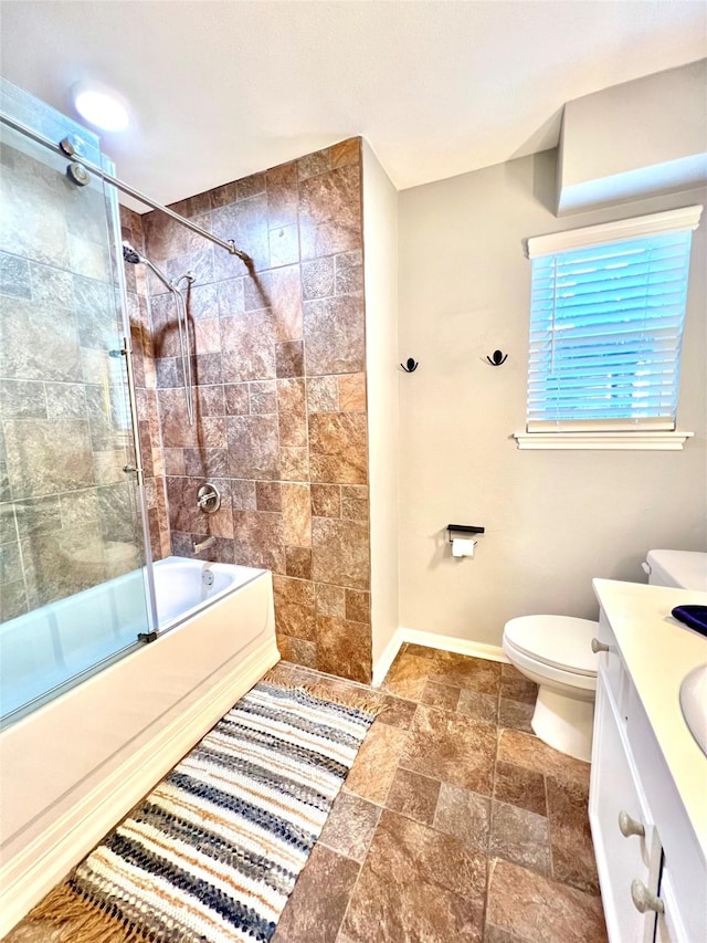 full bathroom featuring bath / shower combo with glass door, toilet, stone finish floor, vanity, and baseboards