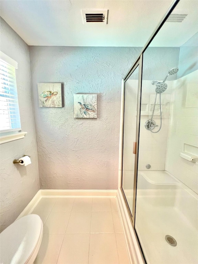 bathroom with visible vents, a textured wall, toilet, tile patterned floors, and a shower stall