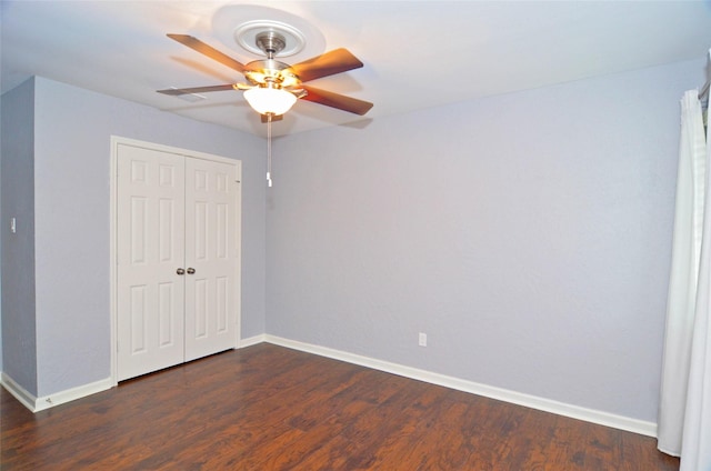 unfurnished bedroom featuring dark wood-type flooring, a closet, a ceiling fan, and baseboards