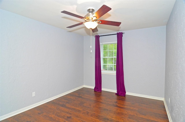 empty room featuring a ceiling fan, baseboards, dark wood-type flooring, and a textured wall