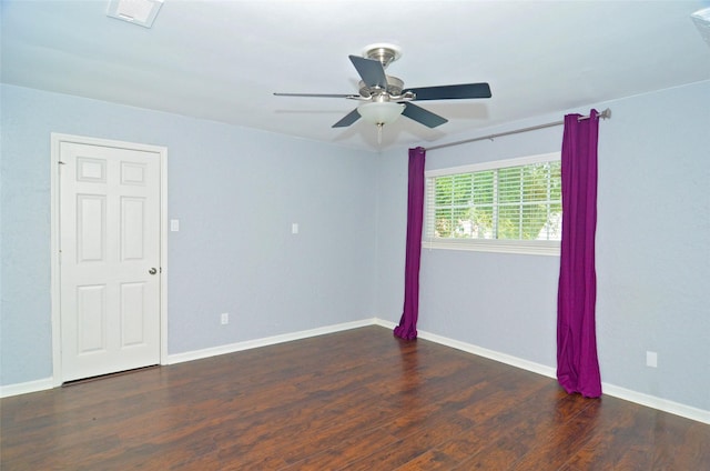 empty room featuring a ceiling fan, dark wood-style flooring, visible vents, and baseboards