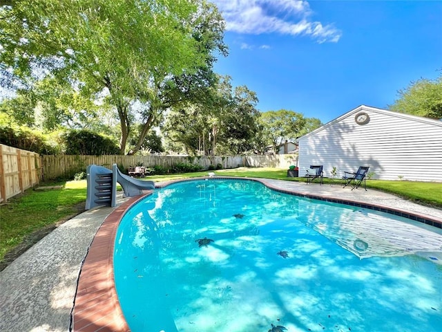 view of pool with a water slide, a fenced backyard, and a lawn