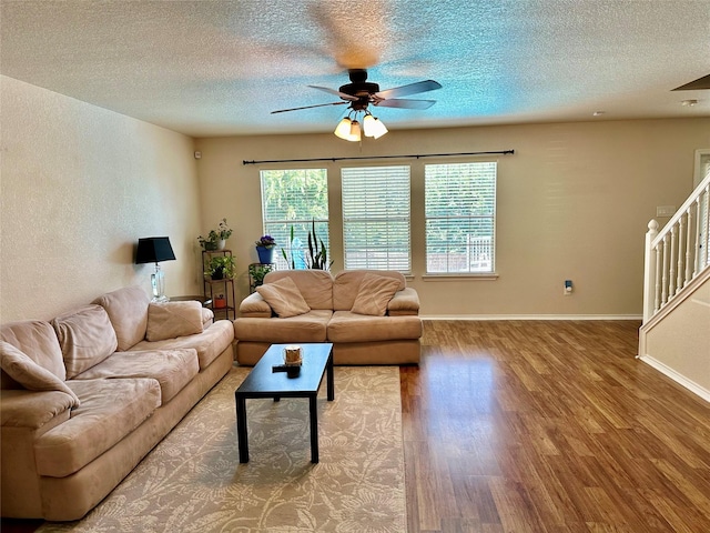 living room with hardwood / wood-style flooring, a textured ceiling, and ceiling fan