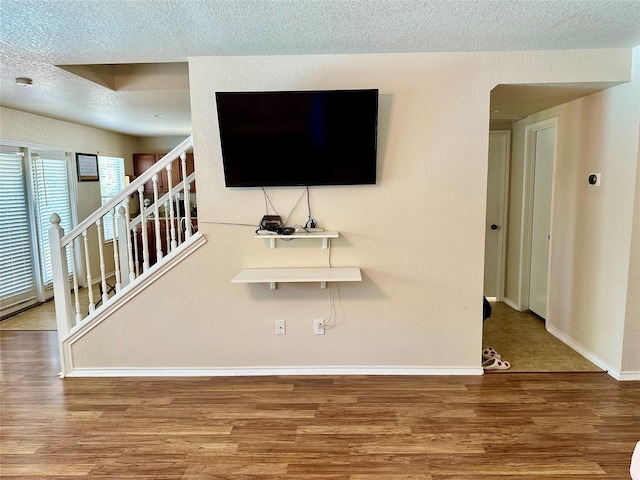 unfurnished living room featuring hardwood / wood-style floors and a textured ceiling