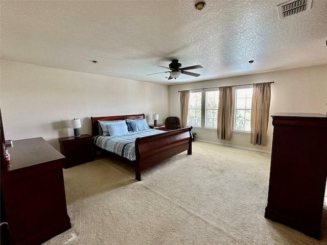 bedroom with ceiling fan, light carpet, and a textured ceiling