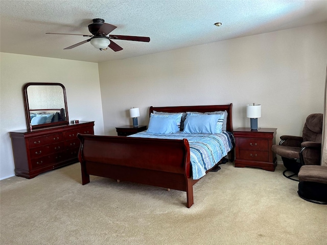 bedroom with ceiling fan, light colored carpet, and a textured ceiling