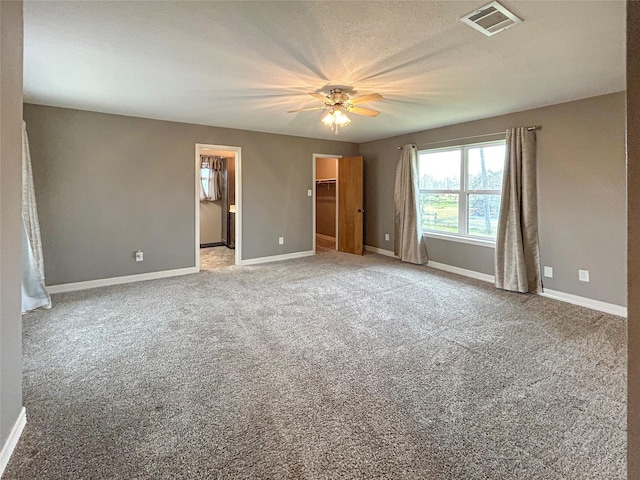 unfurnished bedroom with carpet flooring, visible vents, a spacious closet, and baseboards