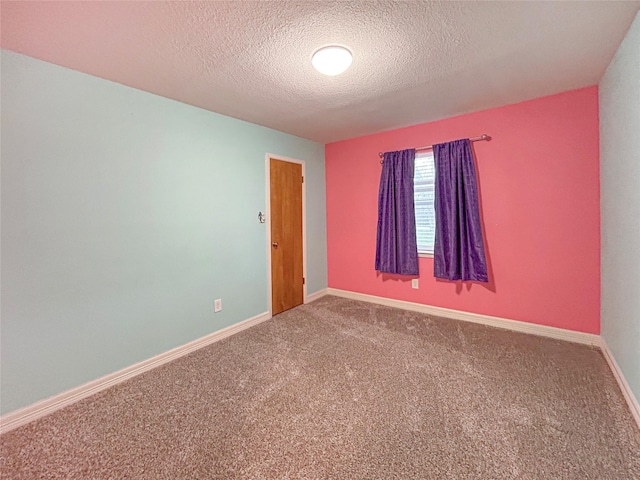 empty room featuring a textured ceiling, carpet floors, and baseboards