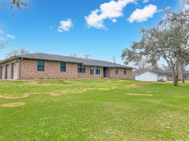 back of property featuring a yard, brick siding, and an attached garage