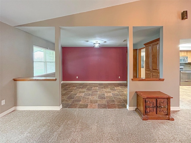 empty room featuring dark colored carpet and baseboards