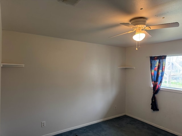 unfurnished room with ceiling fan and dark colored carpet