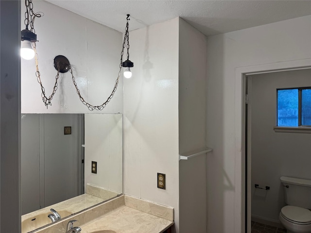 bathroom featuring vanity, toilet, and a textured ceiling