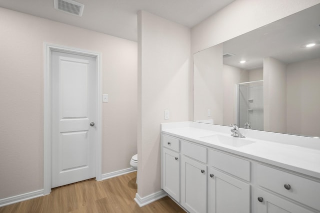 bathroom with vanity, wood-type flooring, toilet, and walk in shower