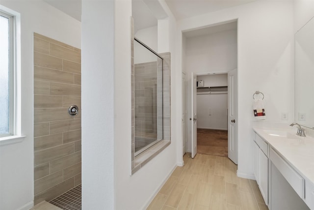 bathroom featuring hardwood / wood-style flooring, vanity, and a tile shower