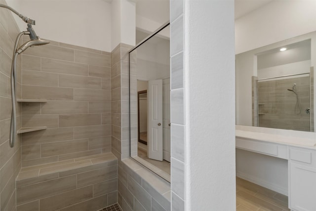 bathroom with hardwood / wood-style flooring, vanity, and tiled shower