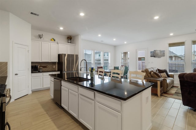 kitchen featuring appliances with stainless steel finishes, an island with sink, sink, white cabinets, and plenty of natural light