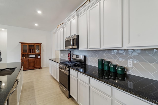 kitchen featuring dark stone countertops, sink, white cabinets, and appliances with stainless steel finishes