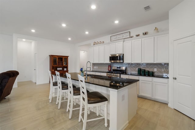 kitchen with a kitchen island with sink, white cabinetry, and stainless steel appliances