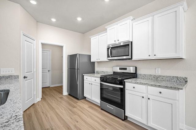 kitchen with white cabinetry, light stone countertops, light hardwood / wood-style floors, and appliances with stainless steel finishes