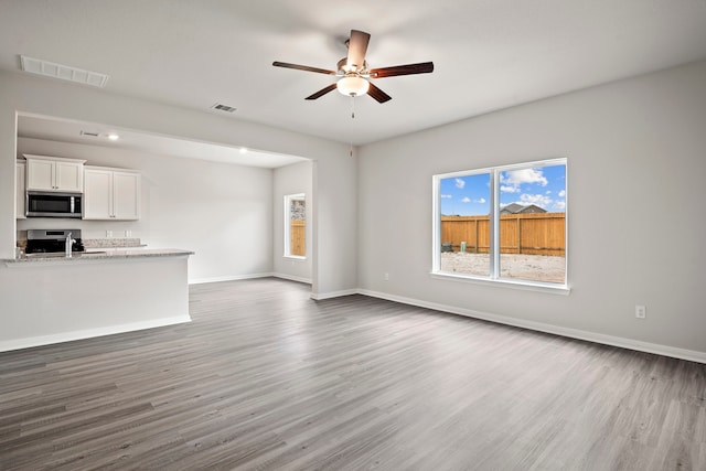 unfurnished living room featuring ceiling fan, dark hardwood / wood-style floors, and sink