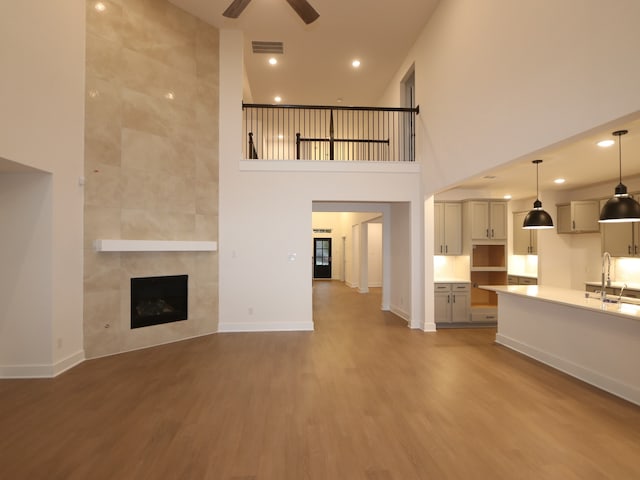8515 Pier Cove Dr, Cypress, TX 77433 - unfurnished living room with a ceiling fan, wood finished floors, a fireplace, recessed lighting, and a high ceiling