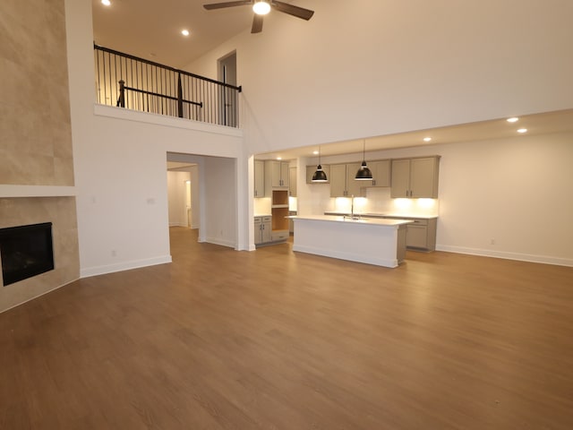 8515 Pier Cove Dr, Cypress, TX 77433 - unfurnished living room with a ceiling fan, wood finished floors, a tile fireplace, a towering ceiling, and recessed lighting