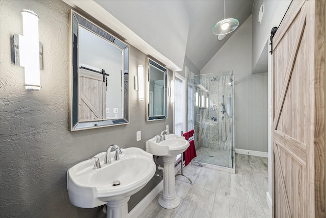 bathroom featuring double sink, a shower with shower door, vaulted ceiling, and hardwood / wood-style floors